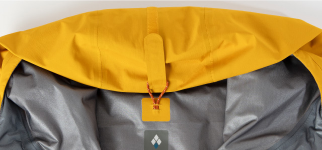 フードに取り付けられたベルクロを襟元のループに通すことで、フードを丸めて首元にまとめた様子